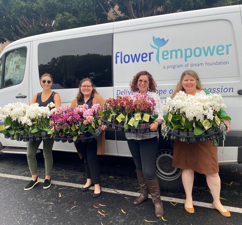 4 helpers in carrying trays of orchids, in front of the Flower Empower van